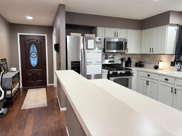 a kitchen with a refrigerator a stove top oven a sink dishwasher and wooden cabinets with wooden floor