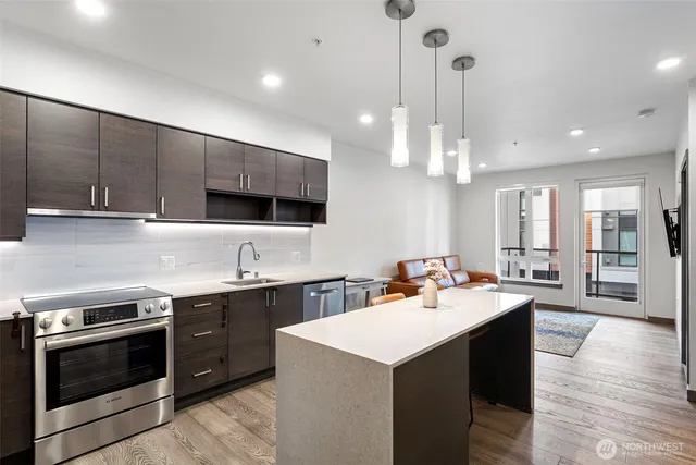 a kitchen with stainless steel appliances a sink a stove a refrigerator and cabinets