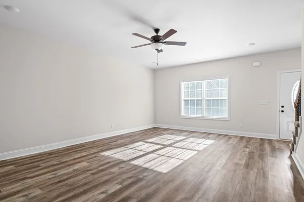 an empty room with wooden floor fan and windows