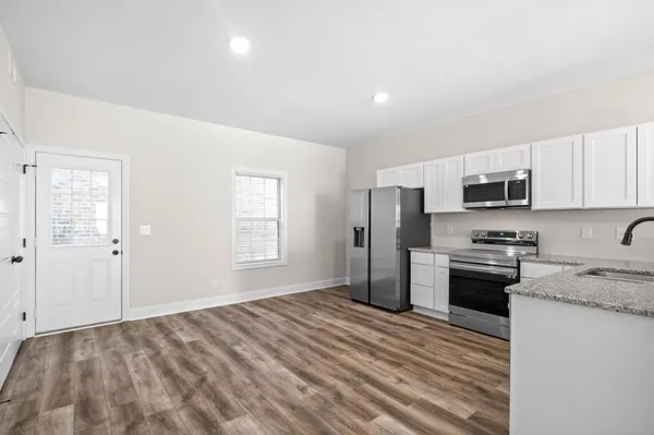 a kitchen with granite countertop a refrigerator stove and oven