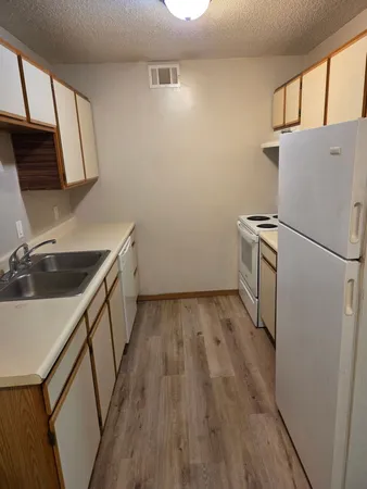 a kitchen with wooden floor sink and refrigerator