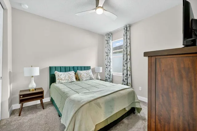 a bedroom with a bed a flat screen tv and a bookshelf