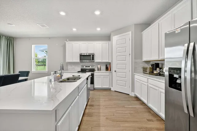 a large kitchen with stainless steel appliances lots of counter space a sink and cabinets