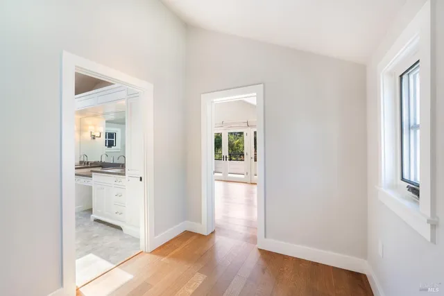 a view of a hallway with wooden floor and a kitchen