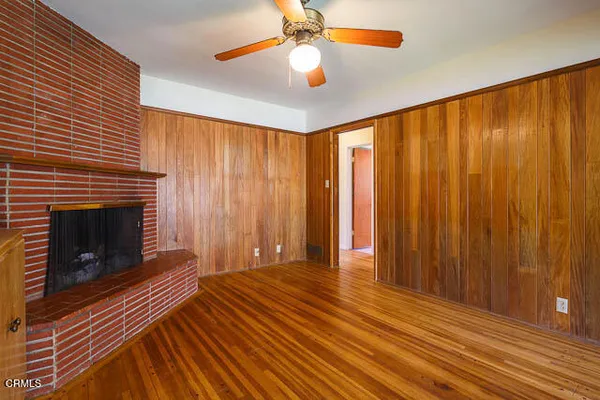 a view of an empty room with wooden floor fireplace and a window