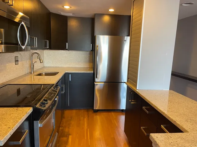 a kitchen with stainless steel appliances granite countertop a sink a stove and a refrigerator