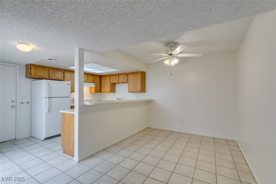 2681 Ruthe Duarte Avenue Las Vegas, NV 89121 - Photo 14 of 43 Kitchen with a peninsula, a textured ceiling, freestanding refrigerator, and ceiling fan