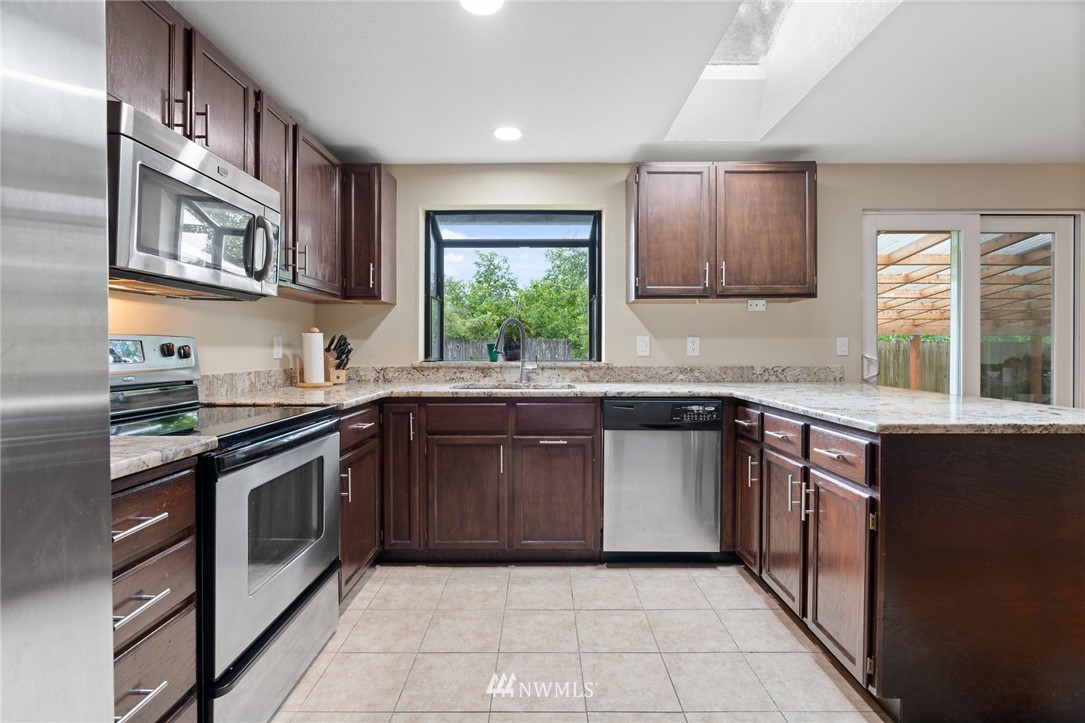 2312 168th Street Southeast Bothell, WA 98012 - Photo 5 of 29 a kitchen with stainless steel appliances granite countertop a stove sink and cabinets