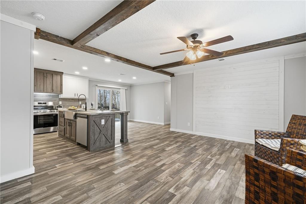 239 Fairview Road Ball Ground, GA 30107 - Photo 18 of 41 a open kitchen with kitchen island a stove a sink dishwasher and a refrigerator with wooden floor