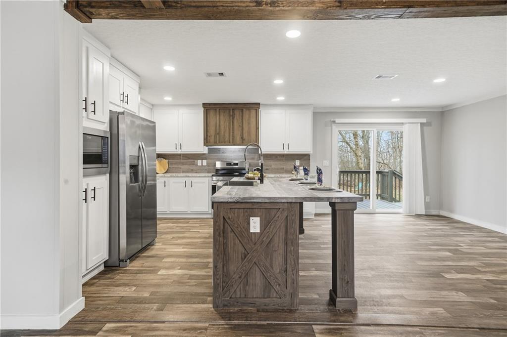 239 Fairview Road Ball Ground, GA 30107 - Photo 20 of 41 a kitchen with stainless steel appliances granite countertop a refrigerator a sink dishwasher a stove with wooden cabinets and floors