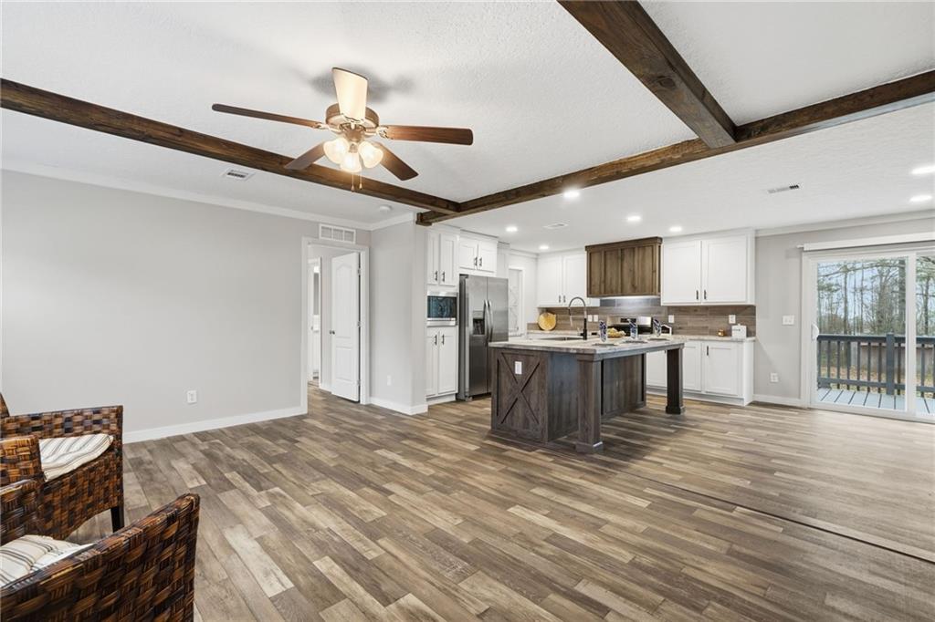 239 Fairview Road Ball Ground, GA 30107 - Photo 22 of 41 a kitchen with stainless steel appliances kitchen island granite countertop a refrigerator a stove top oven a sink dishwasher and white cabinets with wooden floor