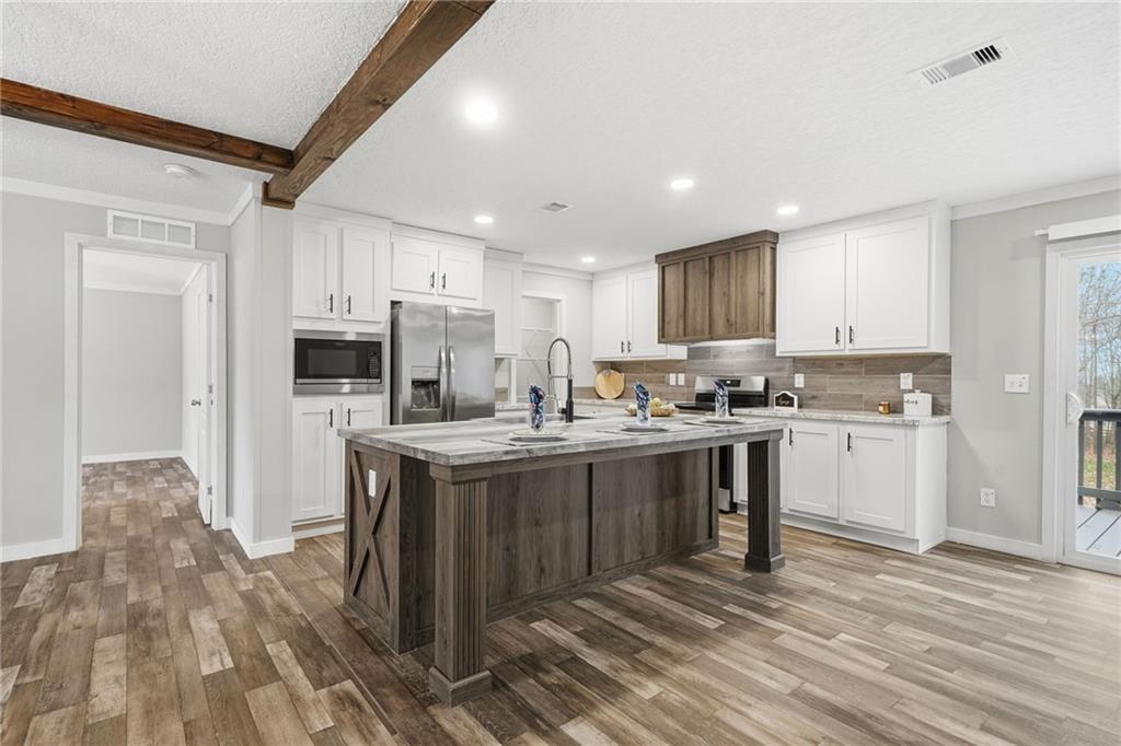 239 Fairview Road Ball Ground, GA 30107 - Photo 23 of 41 a kitchen with kitchen island granite countertop a sink cabinets and stainless steel appliances