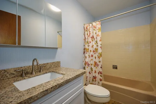 a bathroom with a granite countertop sink toilet and shower