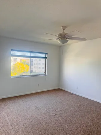 an empty room with a window and a ceiling fan