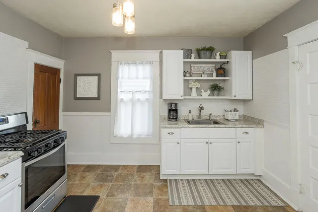 a kitchen with granite countertop a sink cabinets and stainless steel appliances