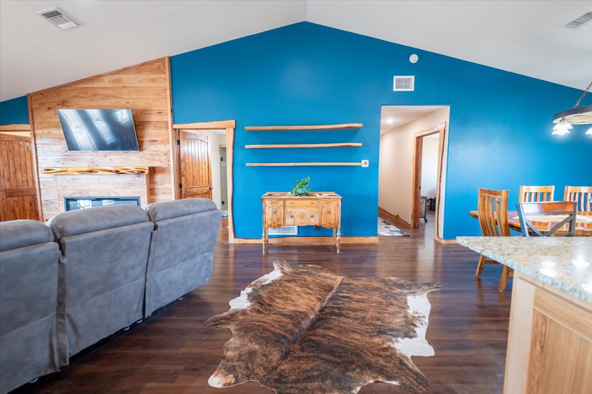 1825 Savanna Ridge Ranch Road Lometa, TX 76853 - Photo 8 of 35 Living area featuring lofted ceiling, dark wood-style flooring, wood walls, and a fireplace
