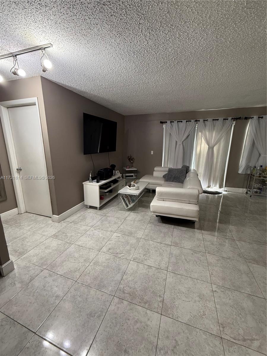 8710 Southwest 3rd Street, Unit 104 Pembroke Pines, FL 33025 - Photo 17 of 46 a living room with furniture a flat screen tv and white walls