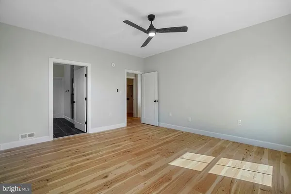 a view of a room with wooden floor and a ceiling fan