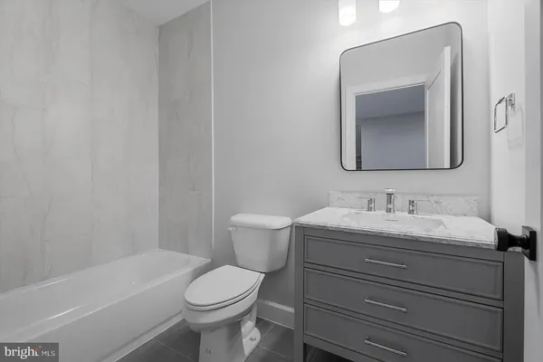 a bathroom with a toilet sink vanity tub and mirror