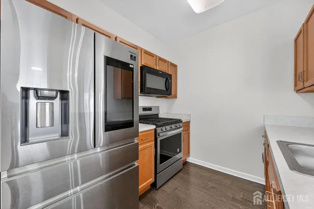 a kitchen with stainless steel appliances granite countertop a refrigerator a stove and a microwave with wooden floor