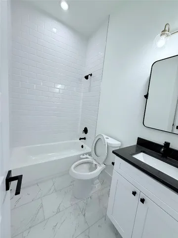 a bathroom with a granite countertop sink a toilet and bathtub