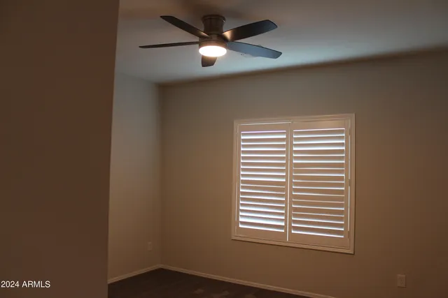 an empty room with window and ceiling fan