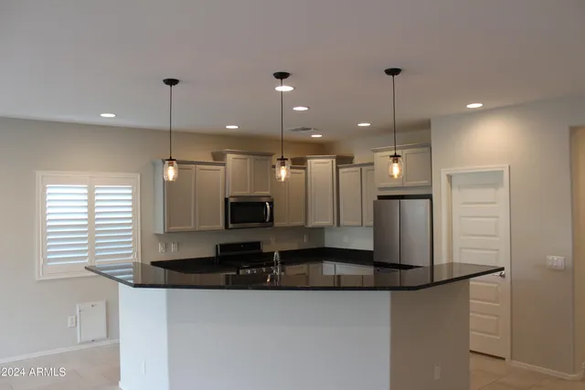 a large kitchen with a large counter top space a sink stainless steel appliances and cabinets