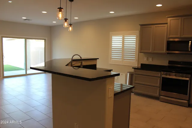 a kitchen with kitchen island granite countertop a sink and a stove top oven with wooden floor
