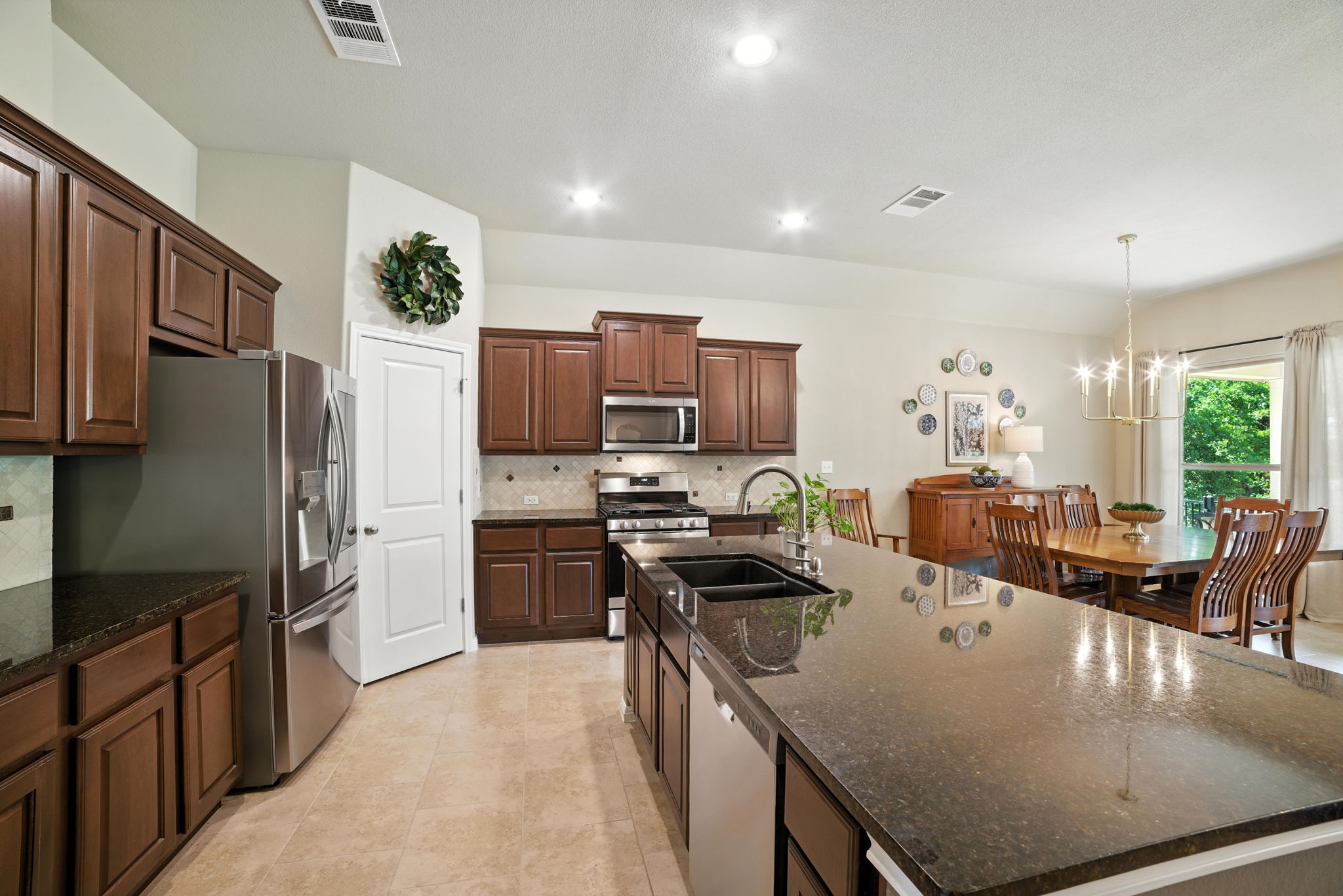 107 Tylee Circle Bastrop, TX 78602 - Photo 20 of 40 Kitchen with decorative backsplash, a large island, appliances with stainless steel finishes, pendant lighting, and a chandelier