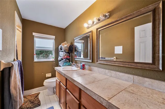 a bathroom with a granite countertop sink mirror vanity and toilet