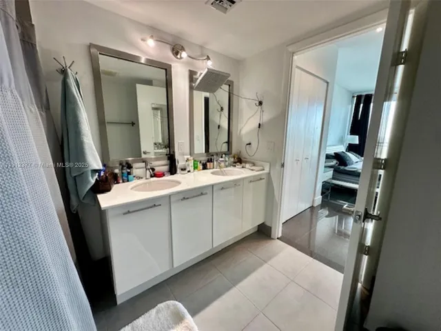 a bathroom with a double vanity sink a mirror and a shower
