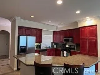 a kitchen with kitchen island granite countertop wooden cabinets a refrigerator a stove a sink and a oven with wooden floor