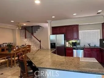 a kitchen with stainless steel appliances granite countertop a refrigerator a stove a sink a dining table and chairs