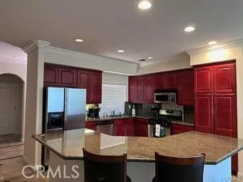 a kitchen with kitchen island granite countertop a stove a sink a refrigerator a dining table and chairs