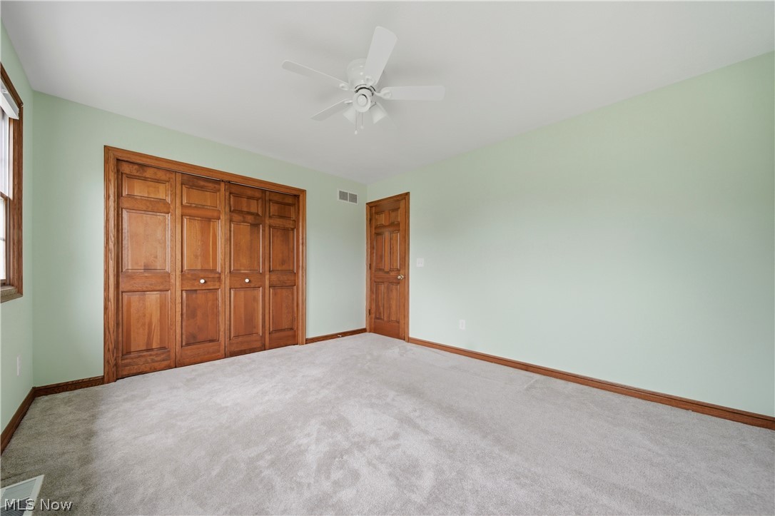 4764 Young Road Stow, OH 44224 - Photo 31 of 41 Carpeted interior space featuring a large bi-fold closet with wood-finish doors and trim, a single window, and a ceiling fan