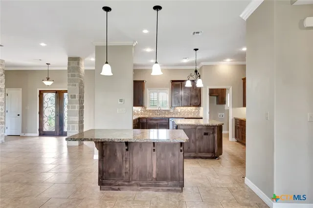 a large kitchen with stainless steel appliances kitchen island granite countertop a large kitchen island a stove a sink a dining table and chairs
