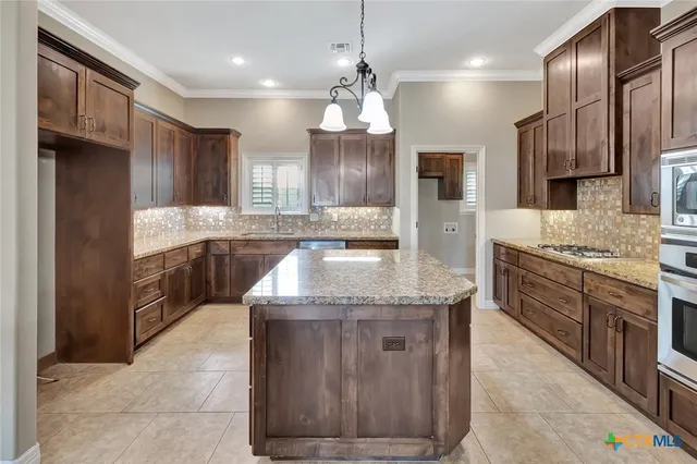 a kitchen with stainless steel appliances granite countertop a sink a stove and a refrigerator