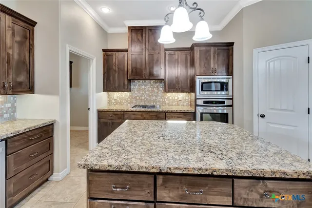 a kitchen with stainless steel appliances granite countertop wooden cabinets and granite counter tops
