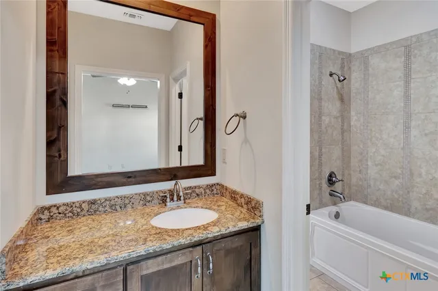 a bathroom with a granite countertop tub sink and mirror