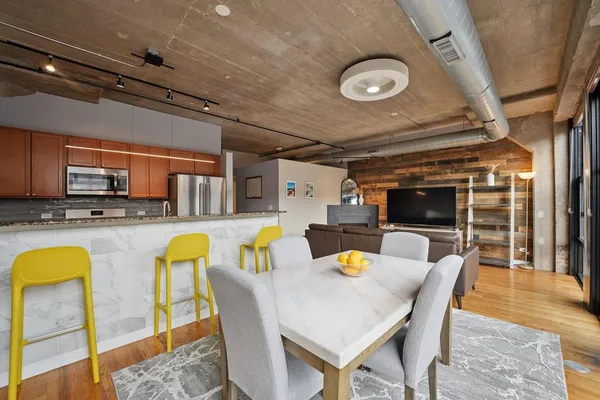 a dining room with stainless steel appliances furniture a fireplace and a open kitchen view