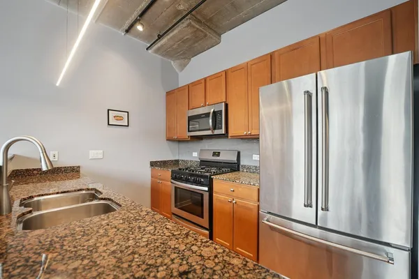 a kitchen with stainless steel appliances granite countertop a refrigerator a stove top oven a sink and dishwasher