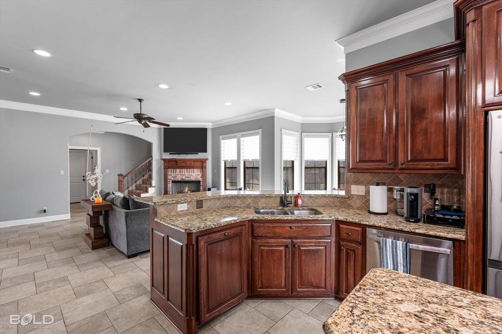 2220 Forest Hills Boulevard Haughton, LA 71037 - Photo 16 of 40 Kitchen featuring dark wood cabinetry, a double basin sink, stainless steel appliances, and granite countertops