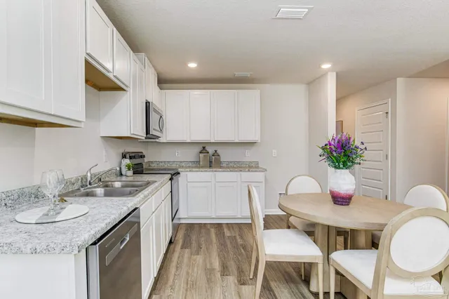 a kitchen with stainless steel appliances granite countertop a sink a stove a dining table and chairs