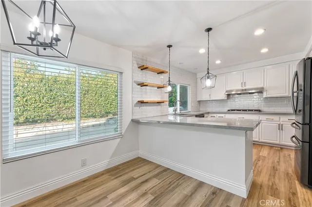 a kitchen with stainless steel appliances granite countertop a sink a stove a refrigerator and island with wooden floor