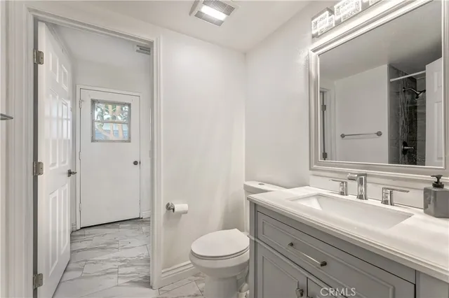 a bathroom with a granite countertop toilet a sink and a mirror