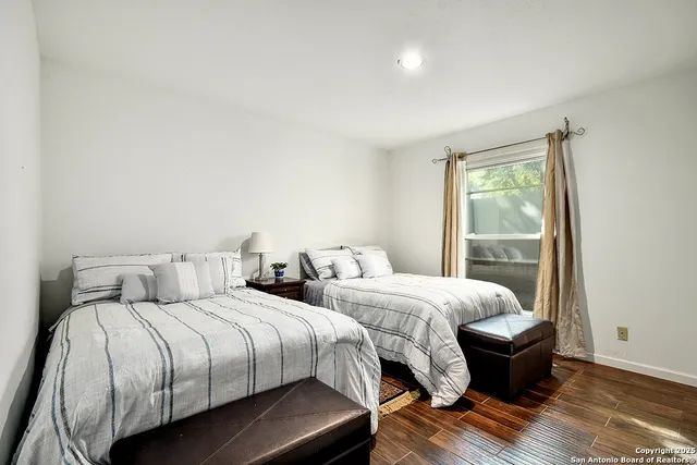 a bedroom with two beds and wooden floor