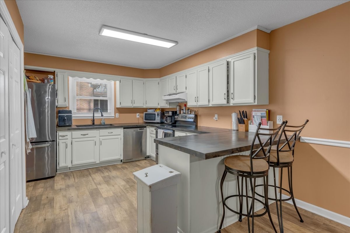 202 Mortons Lake Road Manchester, TN 37355 - Photo 15 of 41 a kitchen with a refrigerator a stove a sink and white cabinets with wooden floor