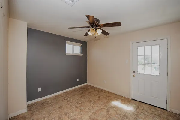 an empty room with windows and fan