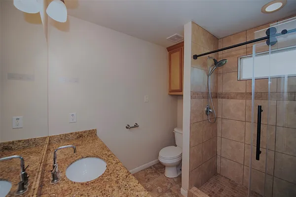 a bathroom with a granite countertop sink mirror vanity and toilet