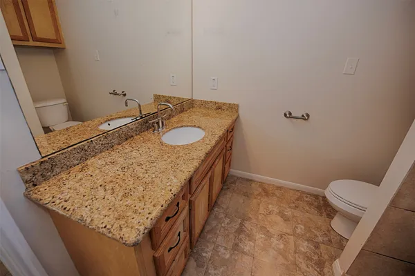 a bathroom with a granite countertop sink and a toilet